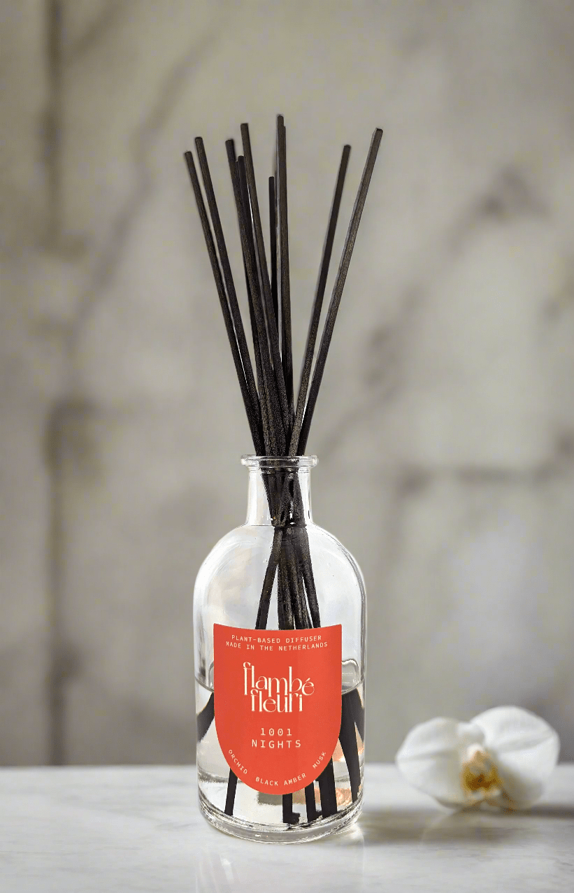 Non toxic Reed Diffuser bottle with black fiber sticks and a red label on a neutral background